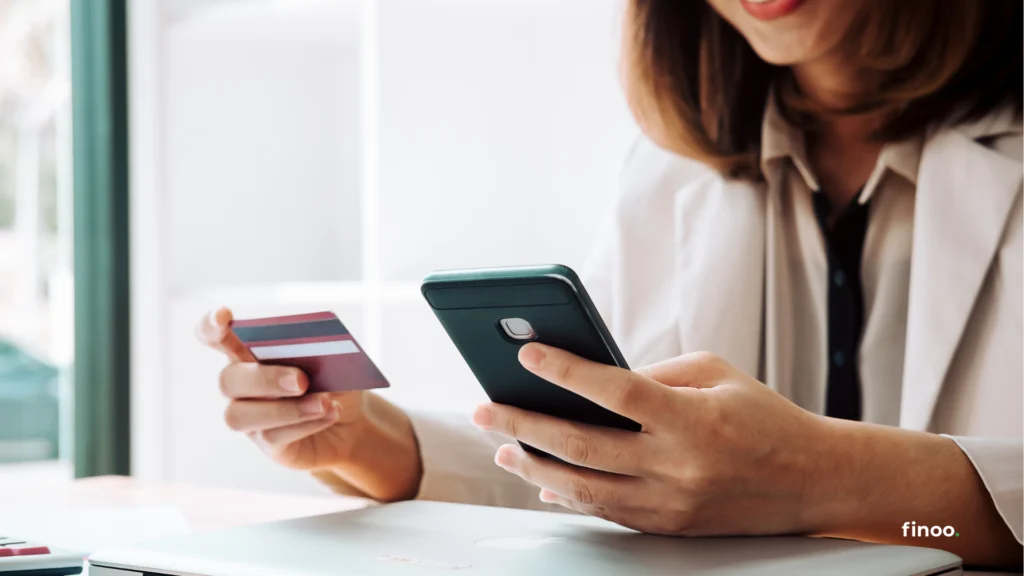 Osoba trzymająca telefon i kartę kredytową – symbol oceny wiarygodności finansowej przy ubieganiu się o kredyt